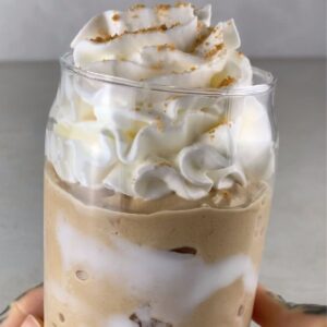 high-protein Ninja Creami Starbucks brown sugar frappuccino in a glass, topped with whipped cream and brown sugar crumbs