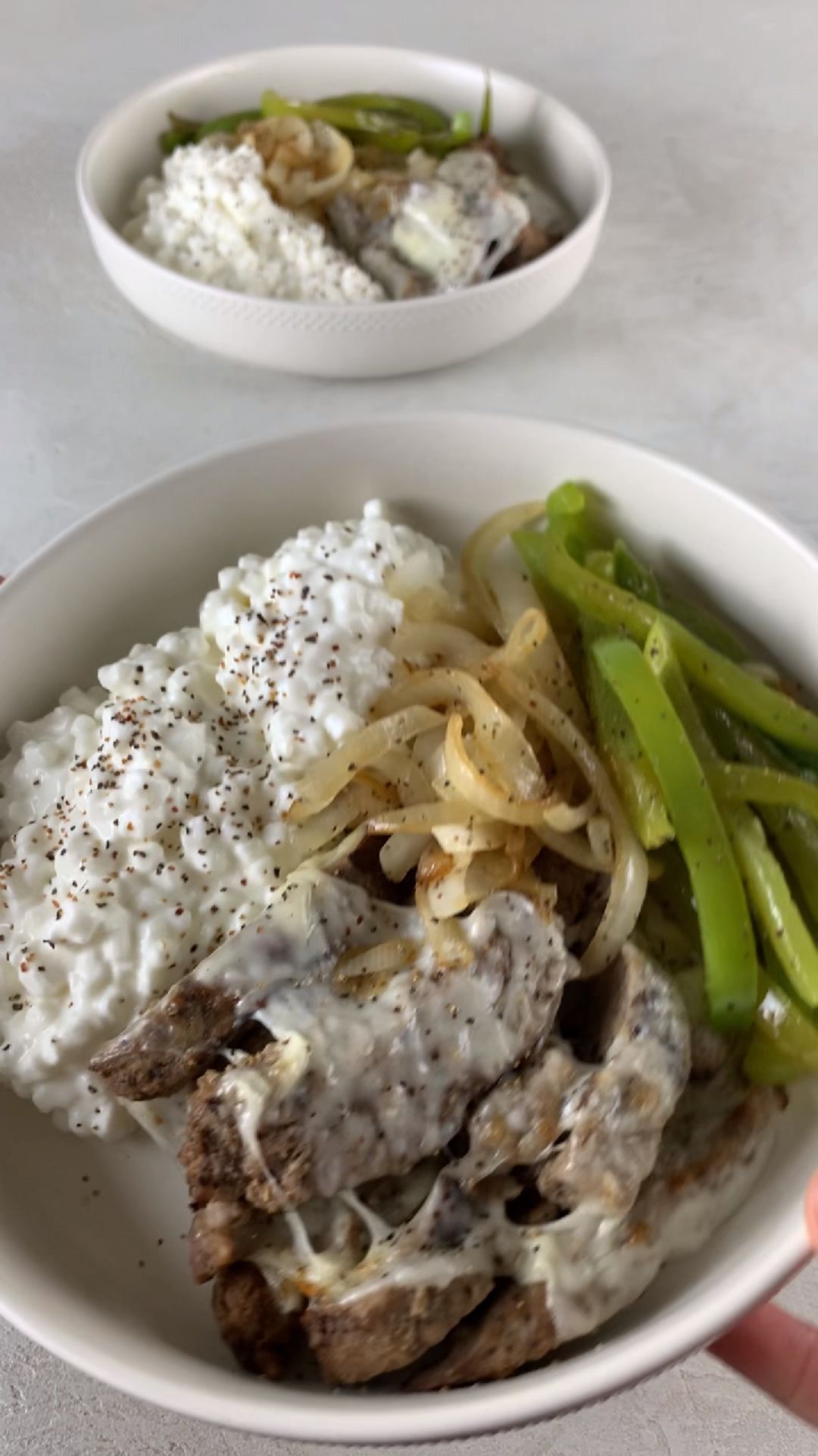 high-protein philly cheesesteak cottage cheese bowl with steak bites, melted provolone, peppers, onions, and cottage cheese