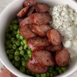 high-protein cottage cheese bowl with sliced sausage and green peas