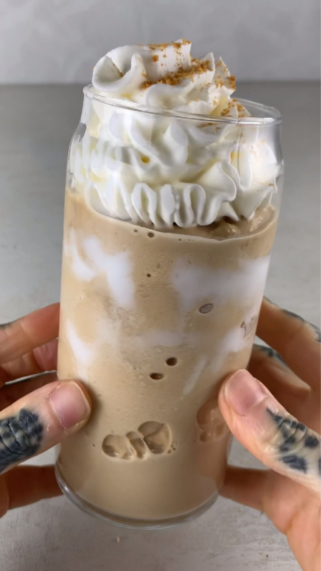 high-protein Ninja Creami Starbucks brown sugar frappuccino in a glass, topped with whipped cream and brown sugar crumbs