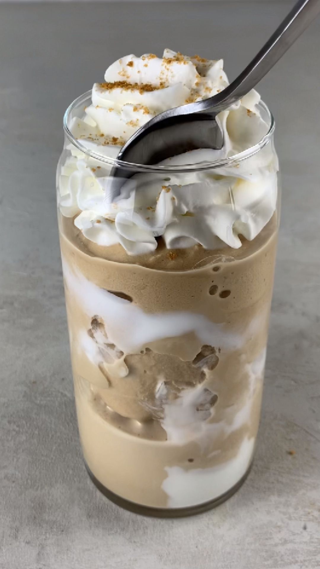 high-protein Ninja Creami Starbucks brown sugar frappuccino in a glass, topped with whipped cream and brown sugar crumbs